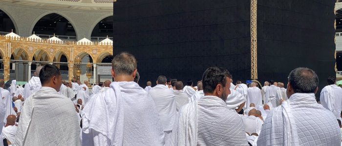 A large group of Muslim pilgrims in white garments gathered around the Kaaba in Mecca. Spirituality and devotion in Saudi Arabia.